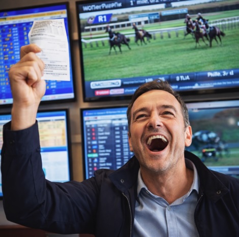 An image of a man winning in a bookmakers waving his winning ticket in the air