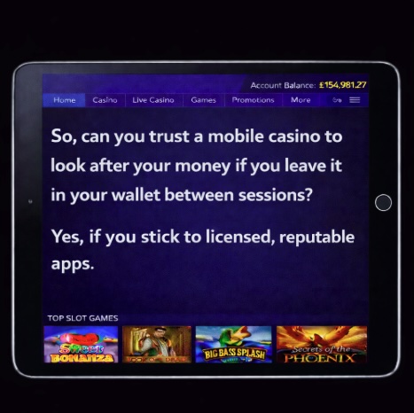 An image of a silver ipad on a black background, on the screen it outlines that YES YOU CAN TRUST A MOBILE CASINO TO LOOK AFTER YOUR MONEY IF YOU STICK TO LICENSED, REPUTABLE APPS in bold white text