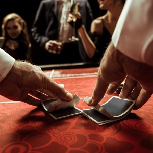 An image of a croupier arms/hands shuffling playing cards on the games table