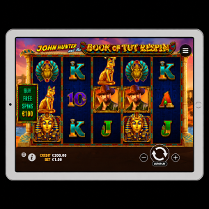 An image of a silver ipad on a black background, on the screen is an image of JOHN HUNTER AND THE BOOK OF TUT RESPIN online slot game