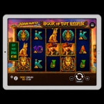 An image of a silver ipad on a black background, on the screen is an online slot image of John Hunter and the Book of Tut ReSpin