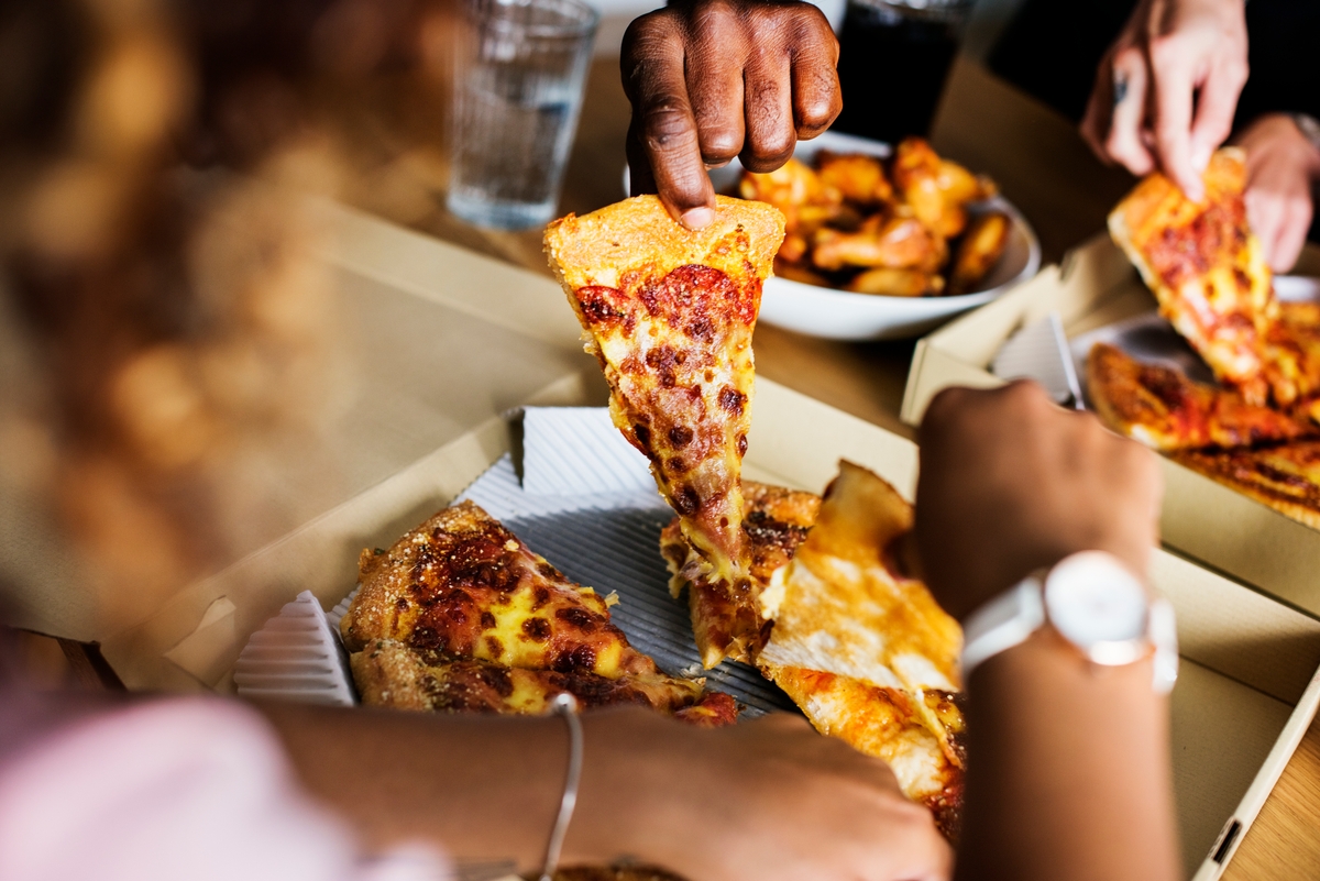 A young woman eating a piece of pizza in the car