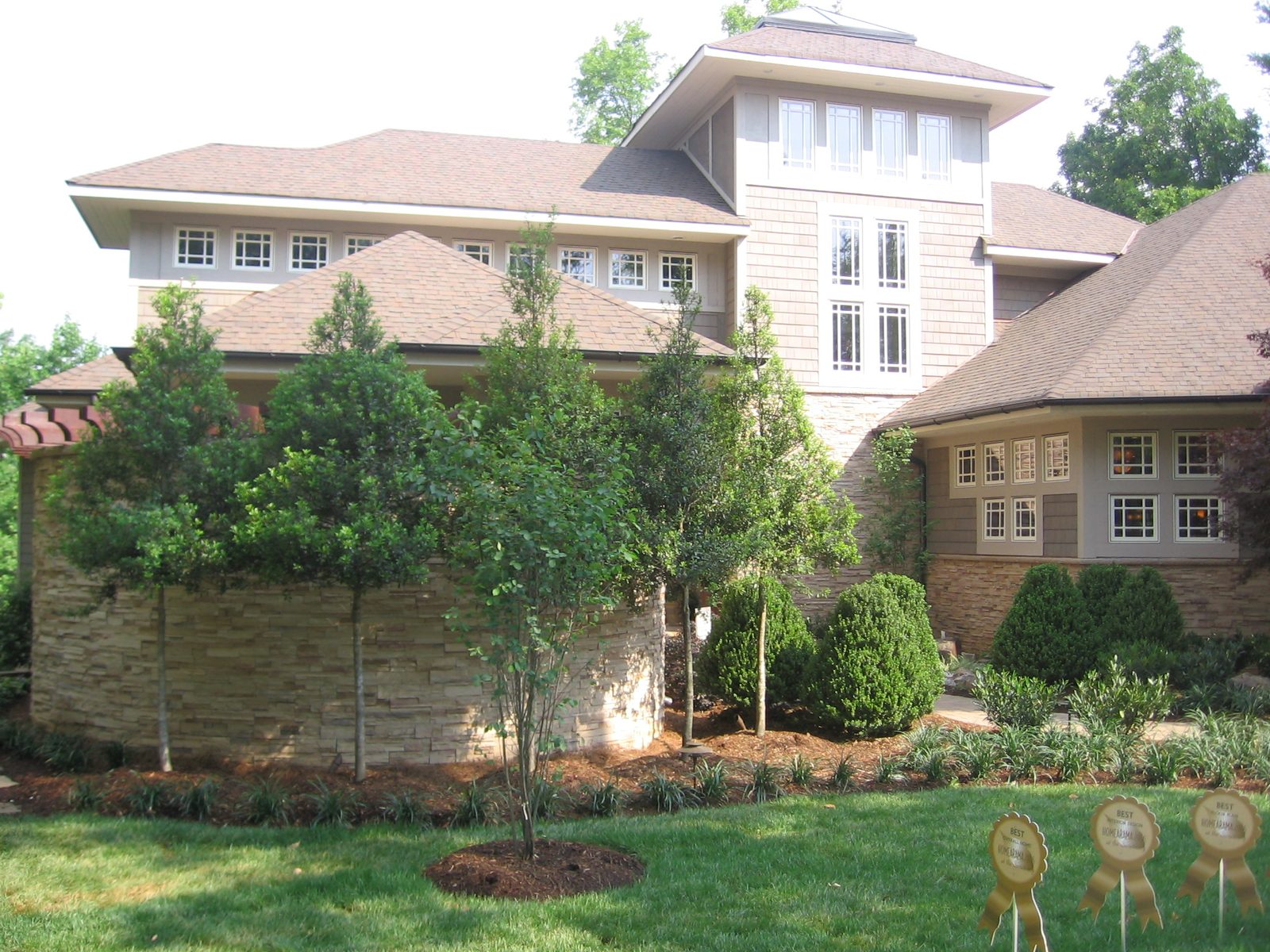 Front of the HomeArama home at The Sanctuary in daylight, with award ribbons in the garden