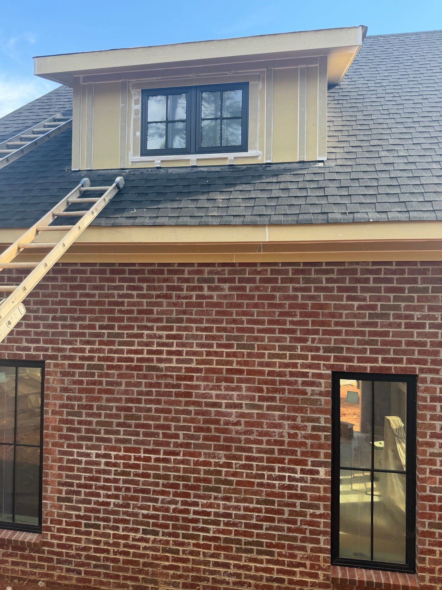 Dormer with board-and-batten siding set into the shingle roof above a brick wall in McLean, Clover SC.