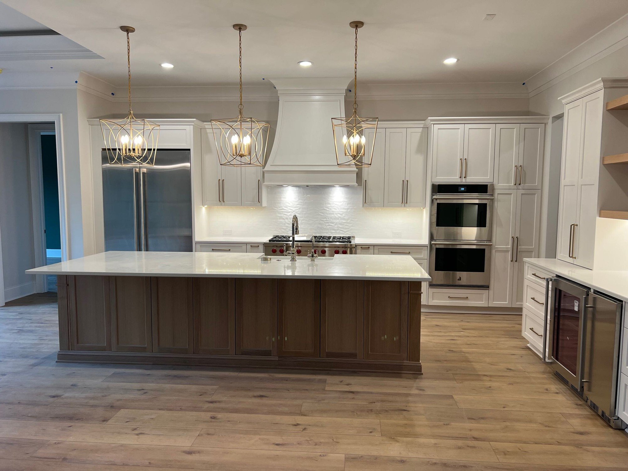Finished kitchen with a wood island, white cabinets and three pendant lights in a home in Montreaux, Charlotte NC.