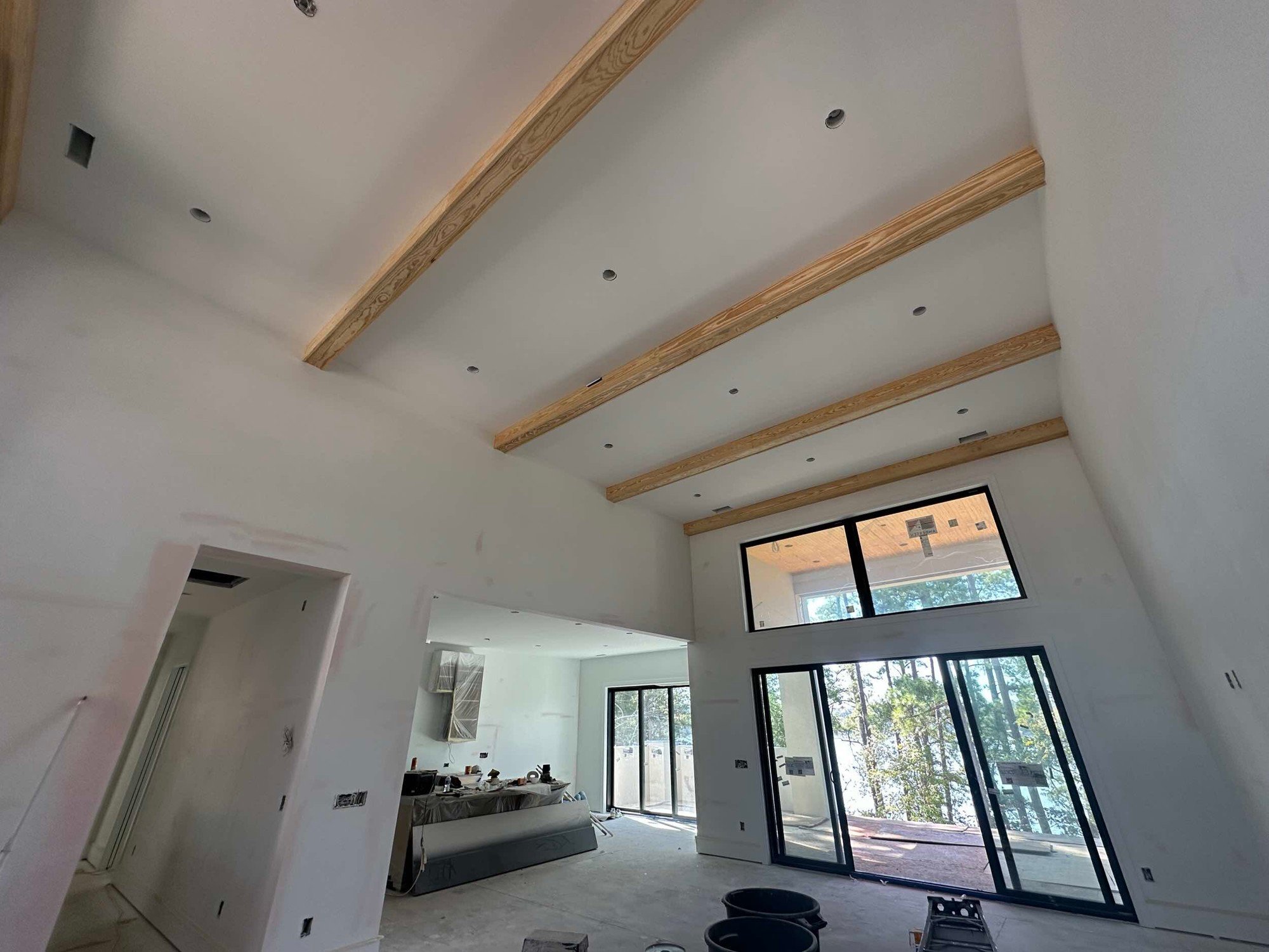 Vaulted room with exposed wood beams and tall black-framed windows.