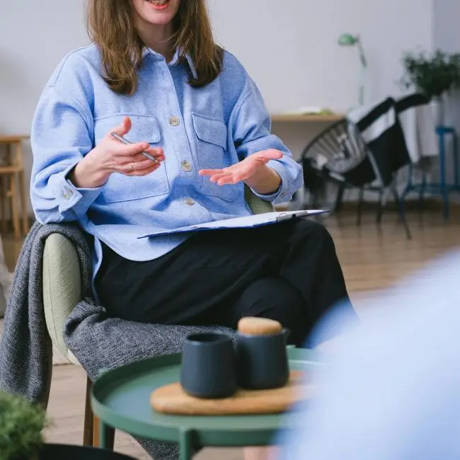 Une personne assise, travaillant sur un ordinateur portable posé sur une table — l’ambiance est sobre et moderne, évoquant le télétravail ou une activité numérique dans un espace calme et épuré.