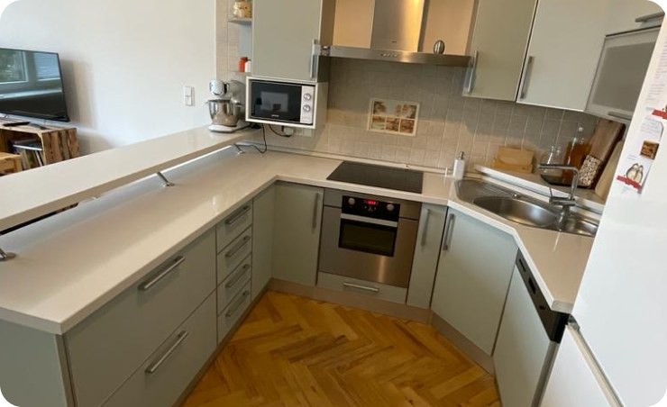 Polepená kuchyň ve světle šedém dekoru s bílou deskou