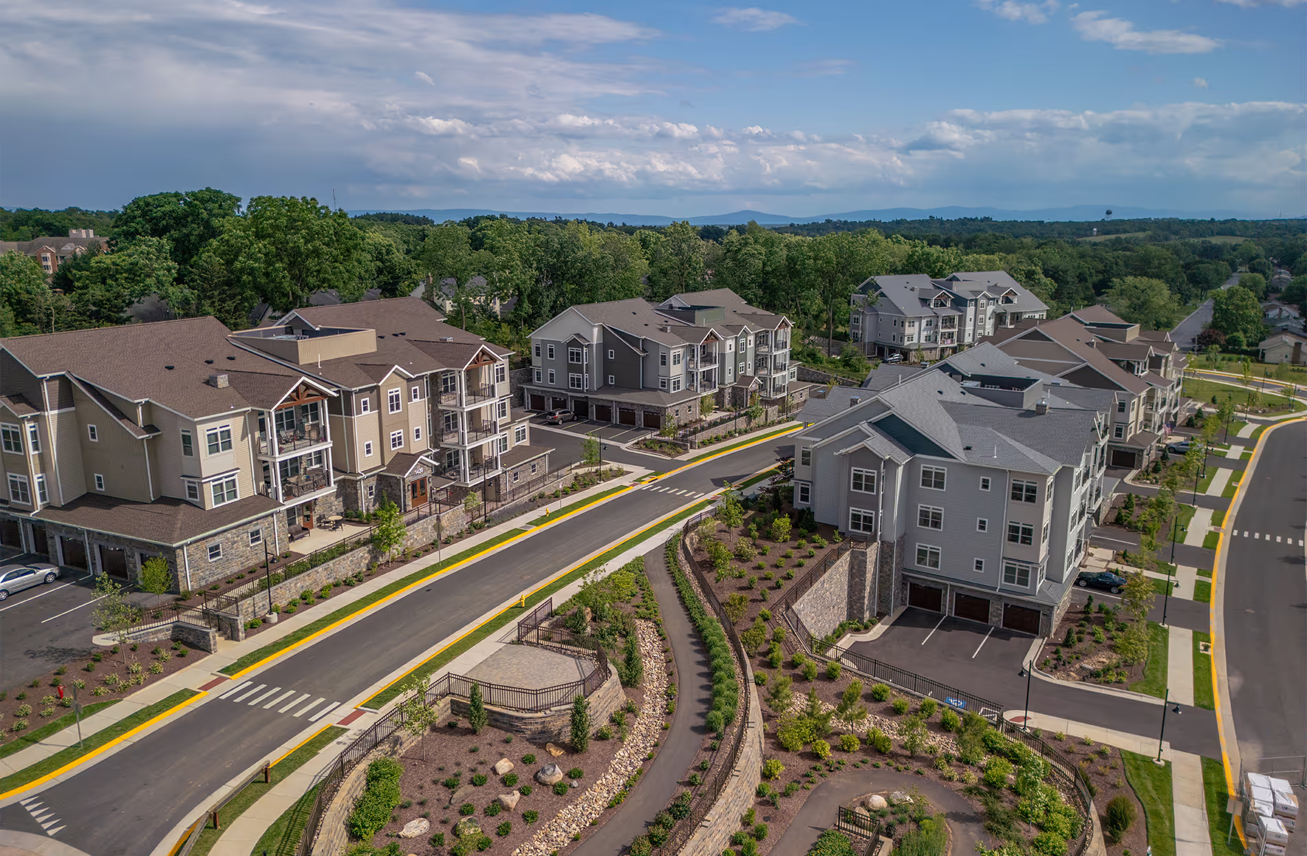 Aerial view of a residential neighborhood with apartment buildings and winding roads lined with landscaping.