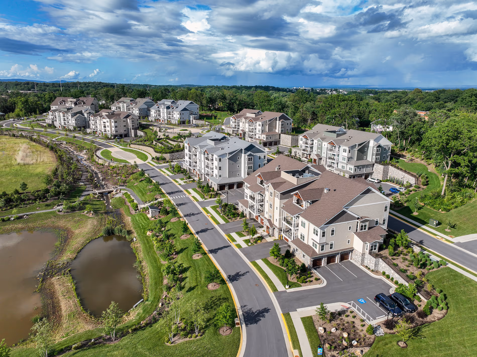 Aerial view of a suburban neighborhood with several apartment buildings surrounded by green trees and roads.