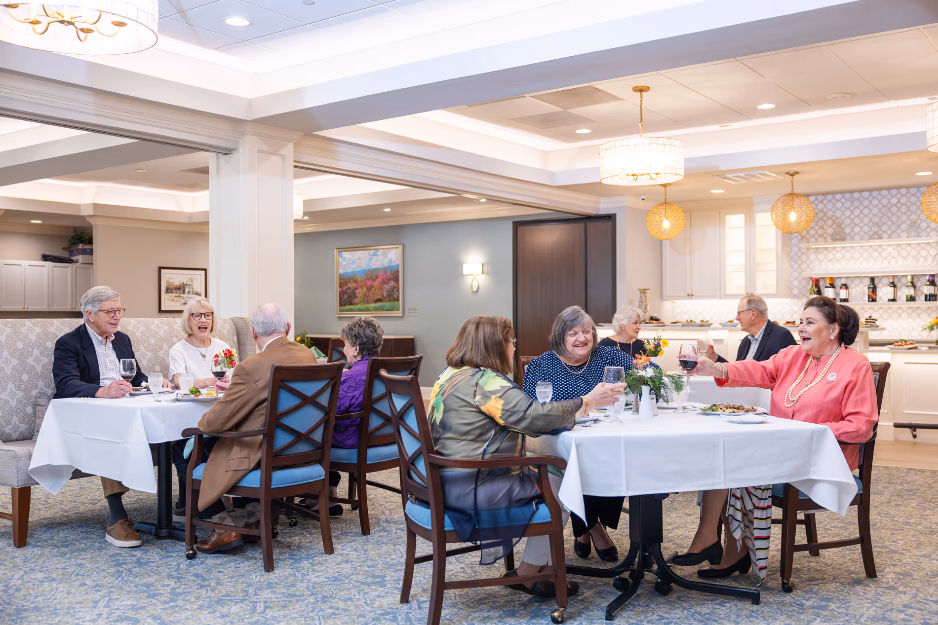 A group of people enjoy a meal together at a restaurant, sitting around two tables.