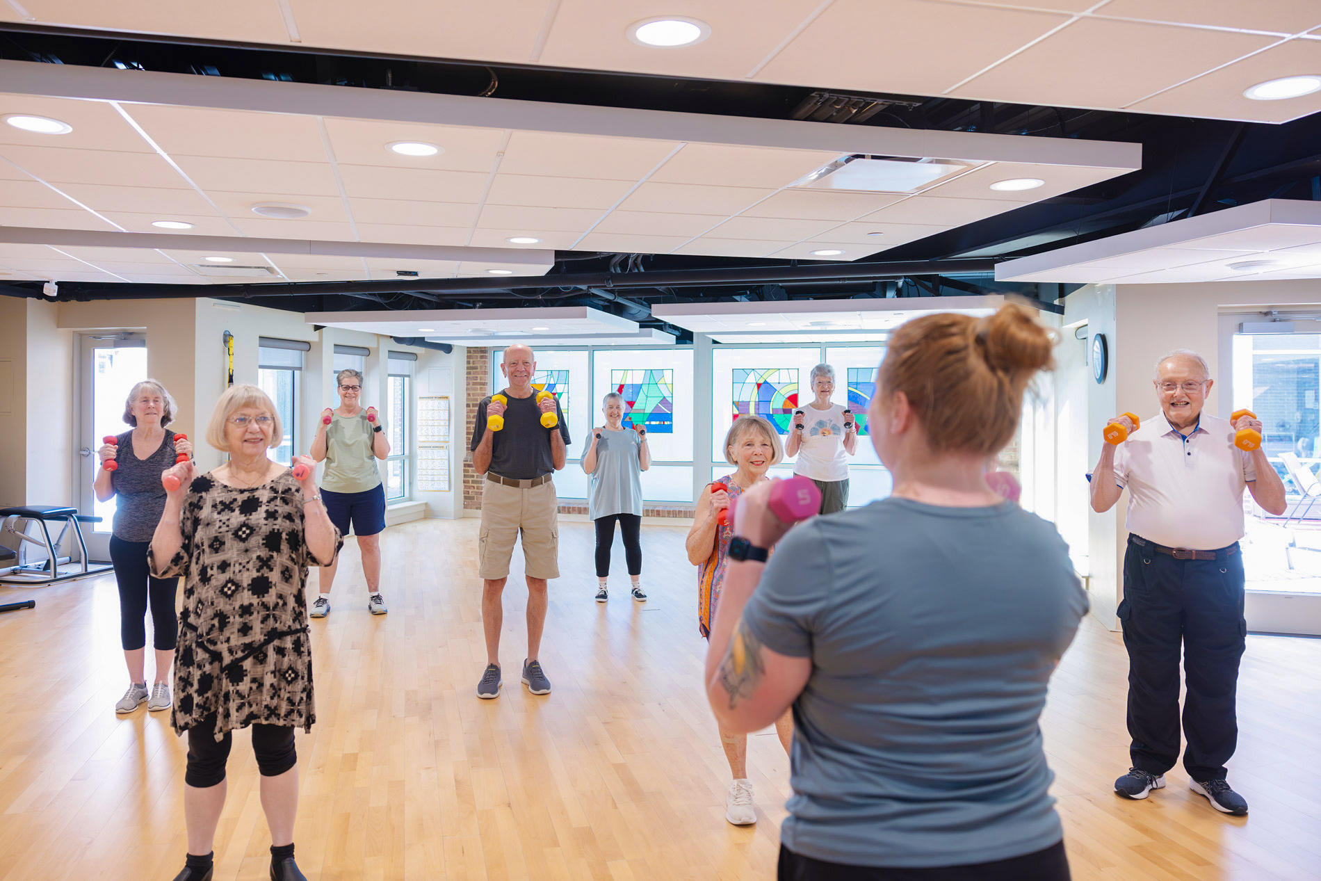 Woman walking a small dog on a sidewalk in a residential neighborhood.