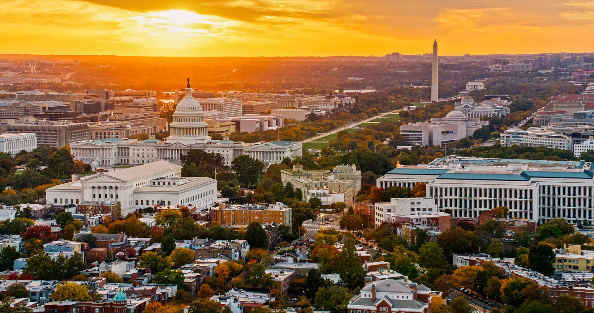 Aerial view of Washington, D.C., featuring the U.S. Capitol, Washington Monument, and nearby buildings at sunset.