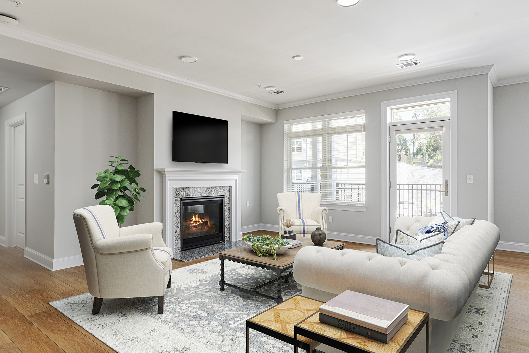 A cozy living room with a lit fireplace, two armchairs, and a sofa around a coffee table.