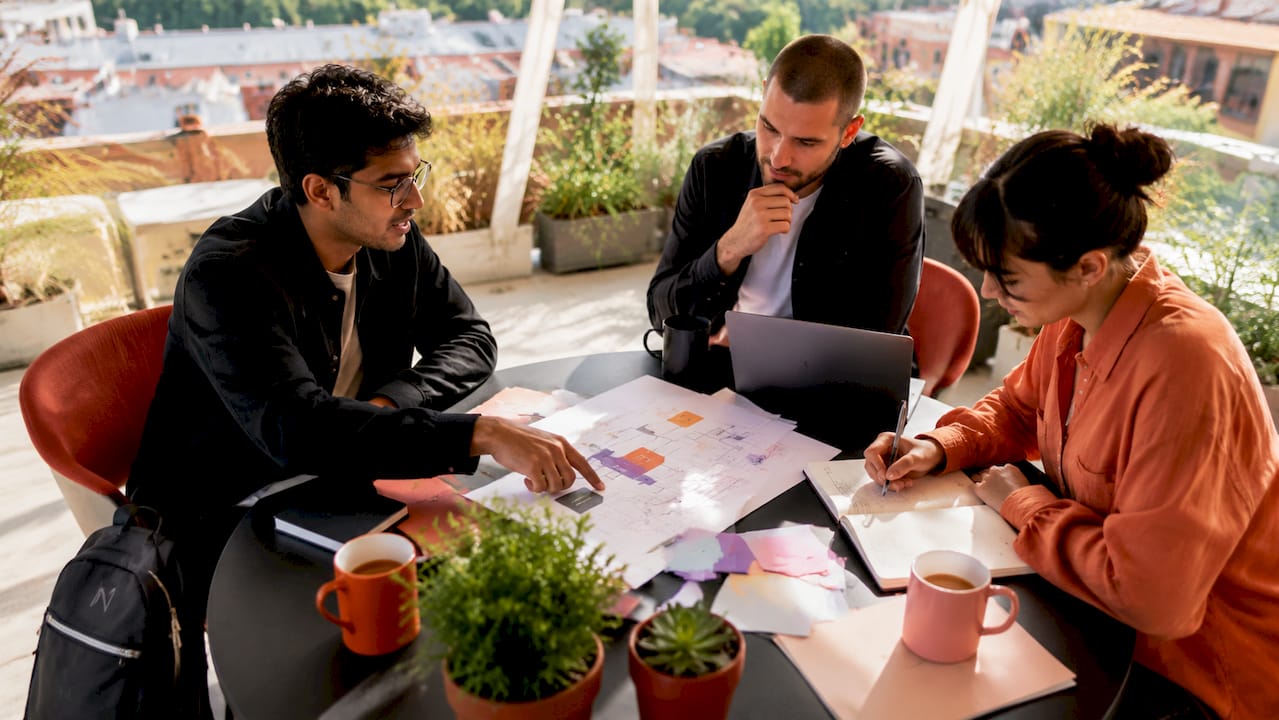 Das Team sitzt zusammen am Tisch und diskutiert die Analyse des Workflows.