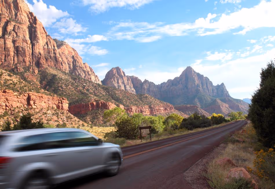 Blurred car driving on road with red rock mountains of Zion National Park