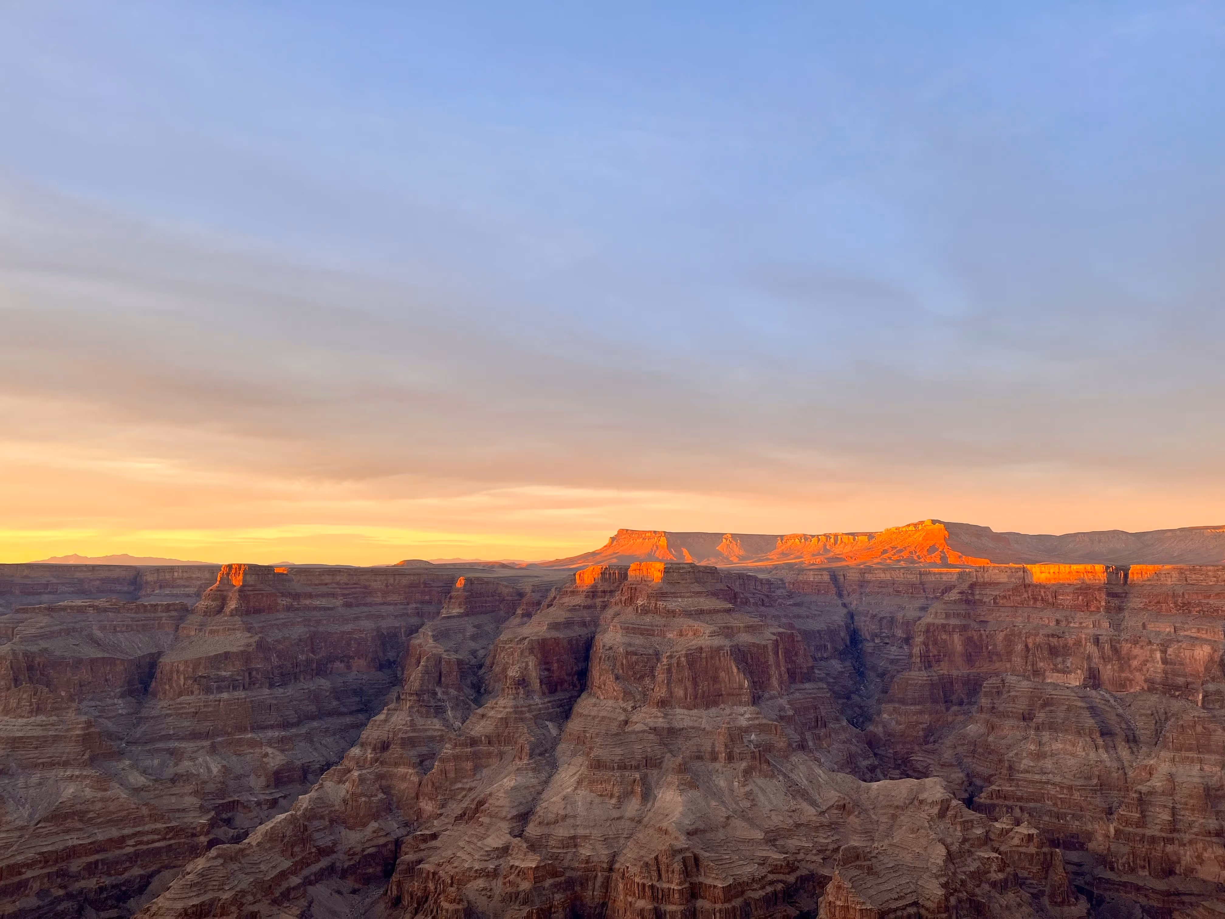 Sunset over Grand Canyon, rocky layers illuminated in warm orange light