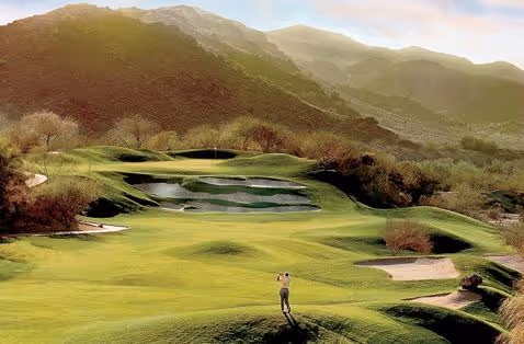 Golfer standing on scenic mountain golf course with lush green fairways