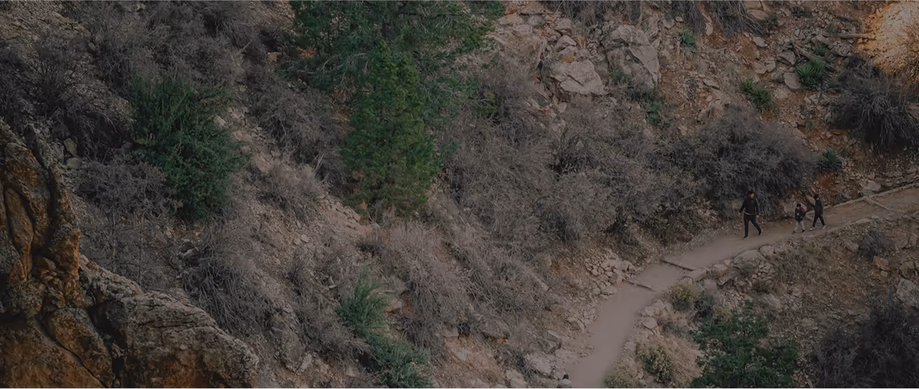 Two hikers walking on rocky trail through rugged mountain terrain