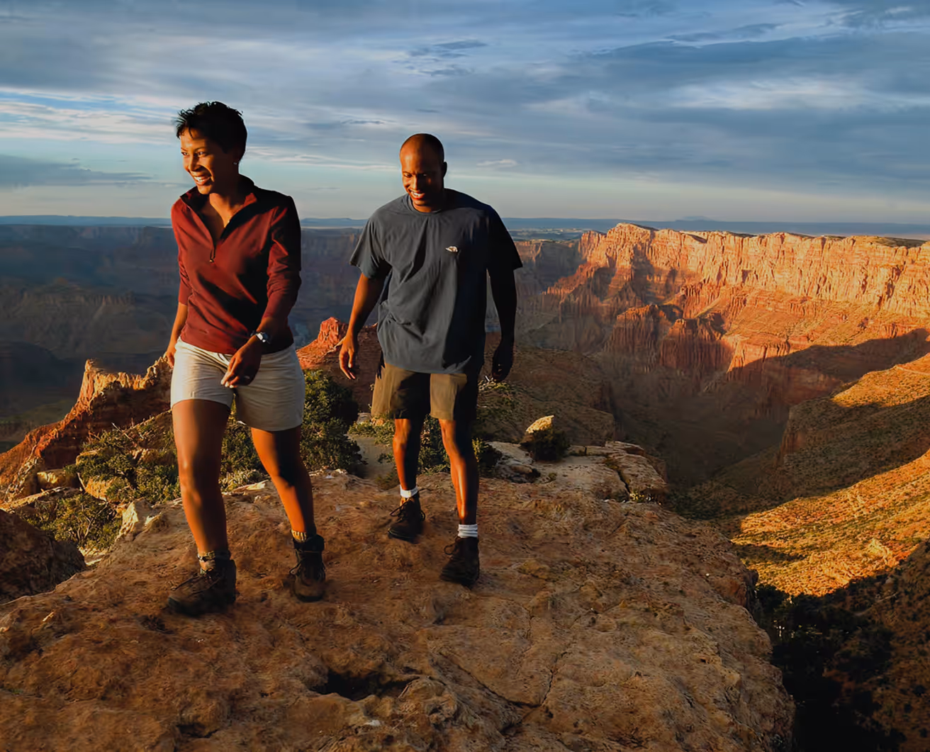 Two hikers enjoy sunset view at Grand Canyon overlook