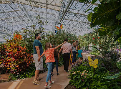 Family walking through colorful botanical greenhouse with lush plants