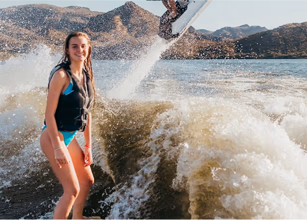 Person wakeboarding on lake with mountains, creating large water splash