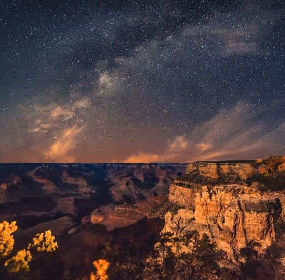 Starry night sky over Grand Canyon with rocky cliffs and Milky Way