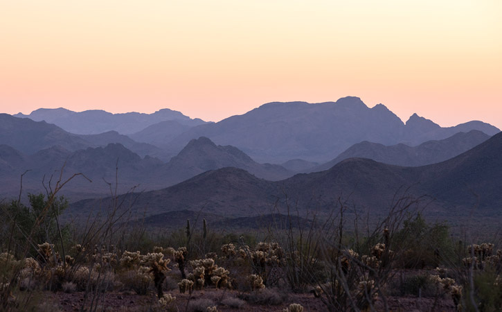 Purple mountain ranges under a yellow-orange sky