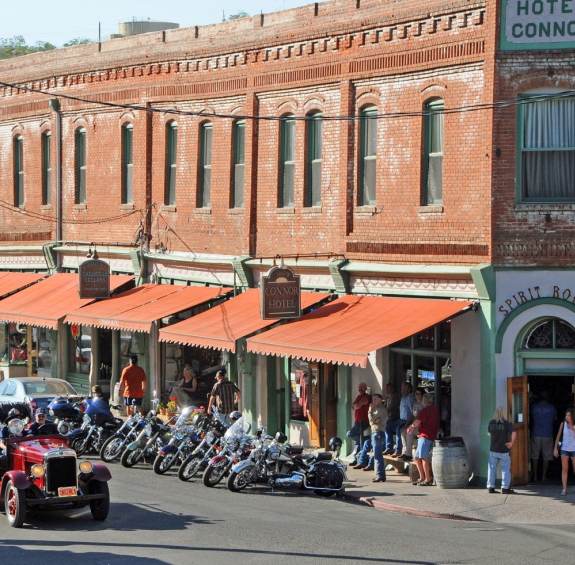 Antique cars and motorcycles drive down Jerome's Main Street outside the historic Hotel Connor. People browse the sidewalk