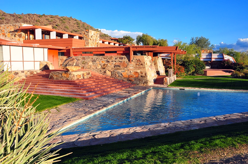 The red wood and stone of Frank Lloyd Wright's Taliesin West is reflected in a triangular pool.
