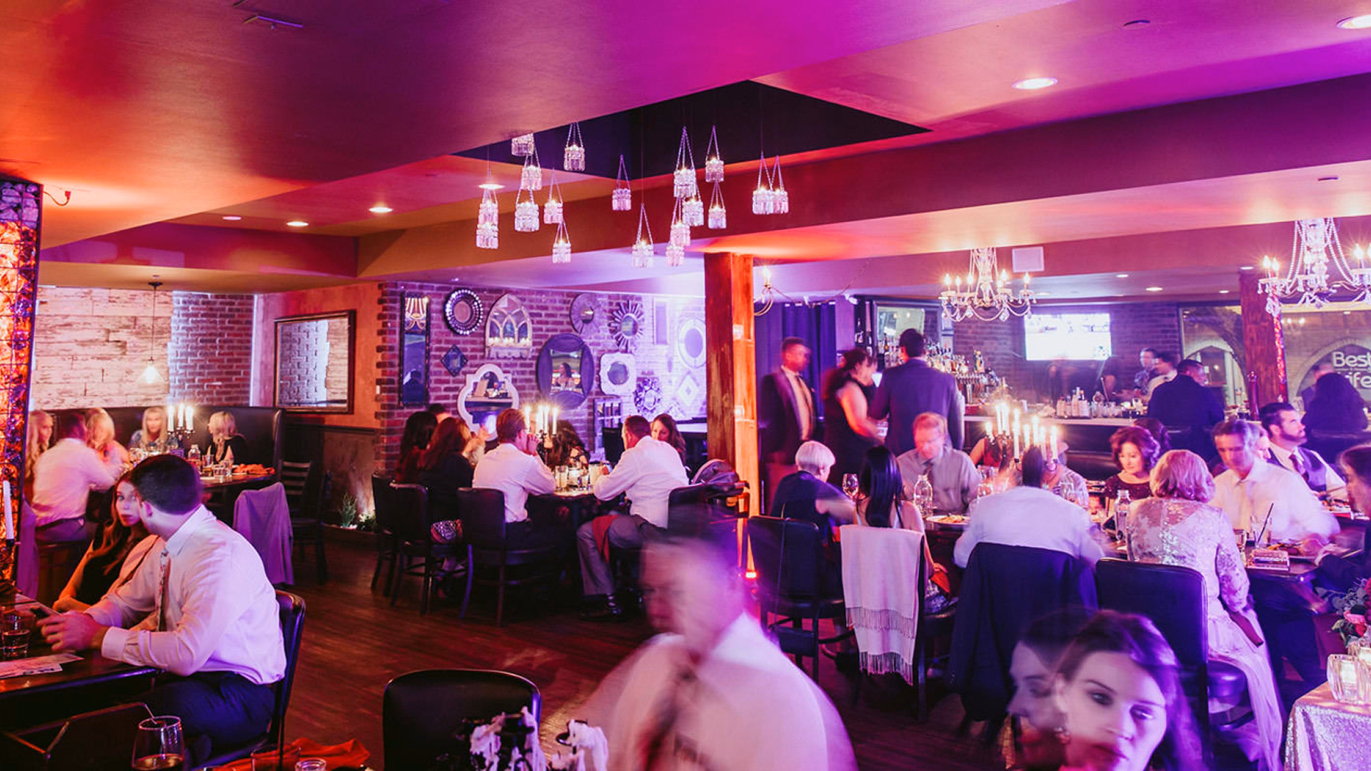 Late night diners gather in a moodily lit restaurant's dining room.