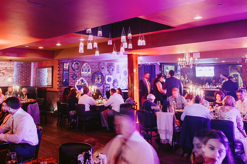Late night diners gather in a moodily lit restaurant's dining room.