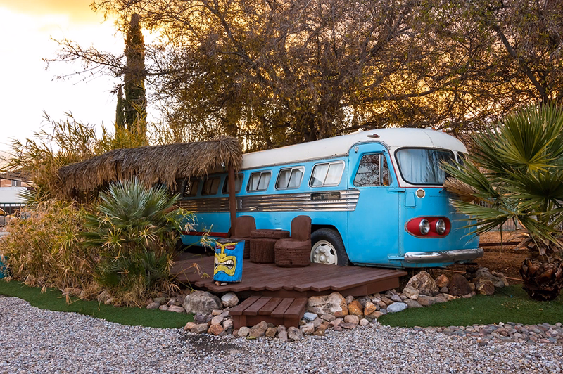 A restored blue bus turned into an accommodation is nestled between palm trees.