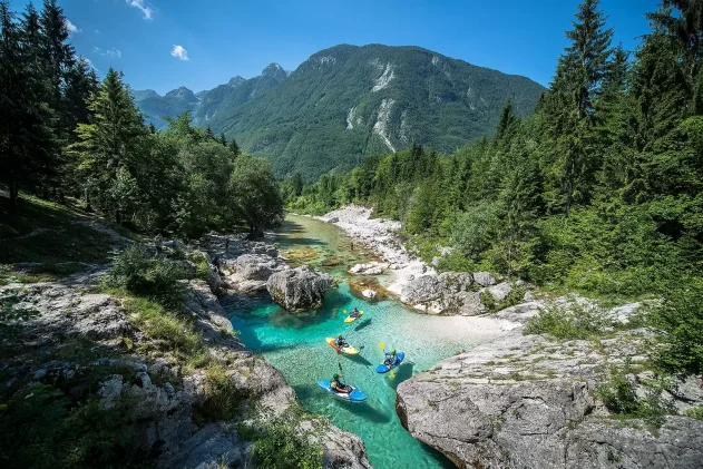 Paddlers on a turquoise mountain river in a forested valley