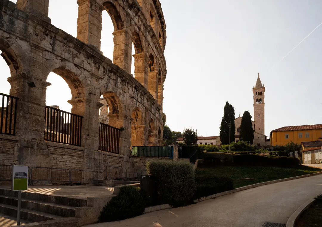 Roman amphitheatre arches with a bell tower in the distance