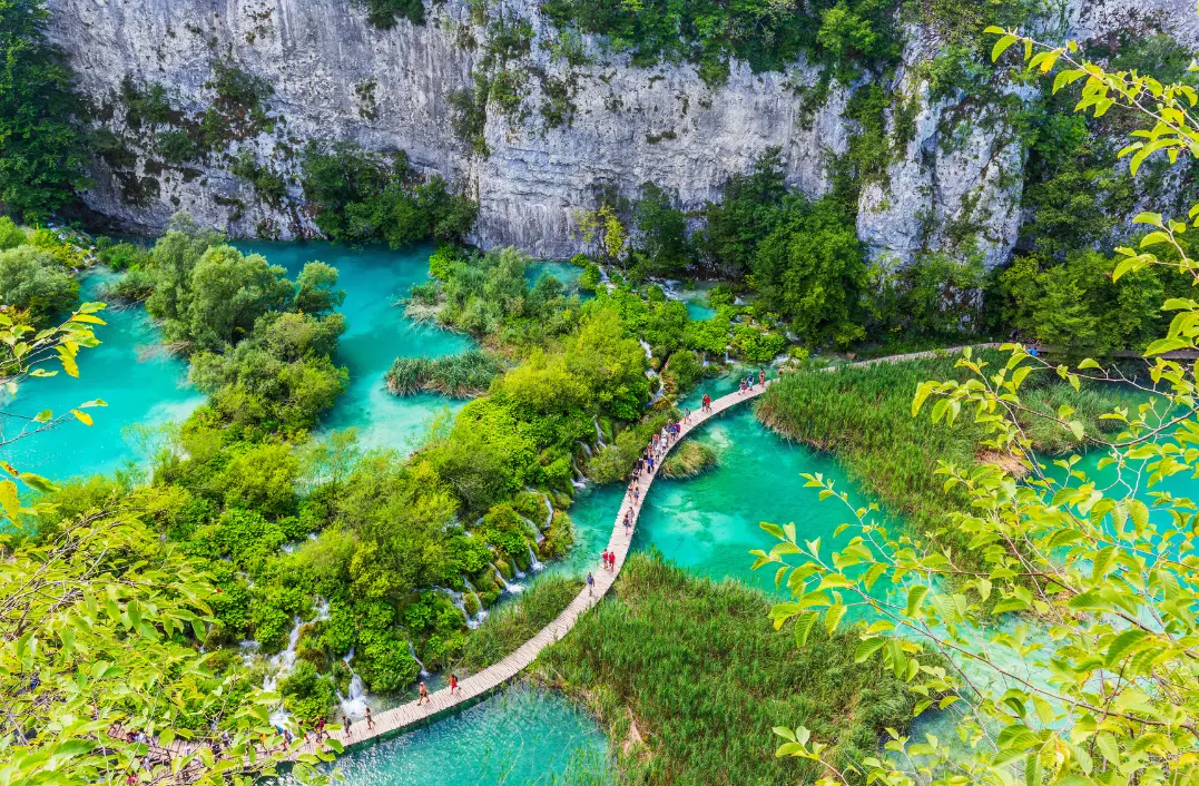 Wooden boardwalk crossing turquoise lakes and small waterfalls
