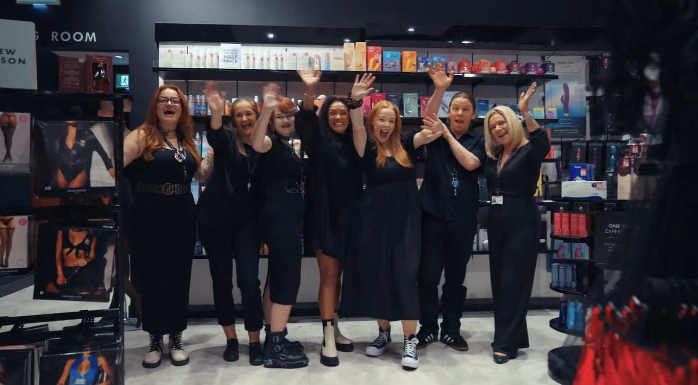 Ann Summers retail employees standing in front of product display and waving at the camera