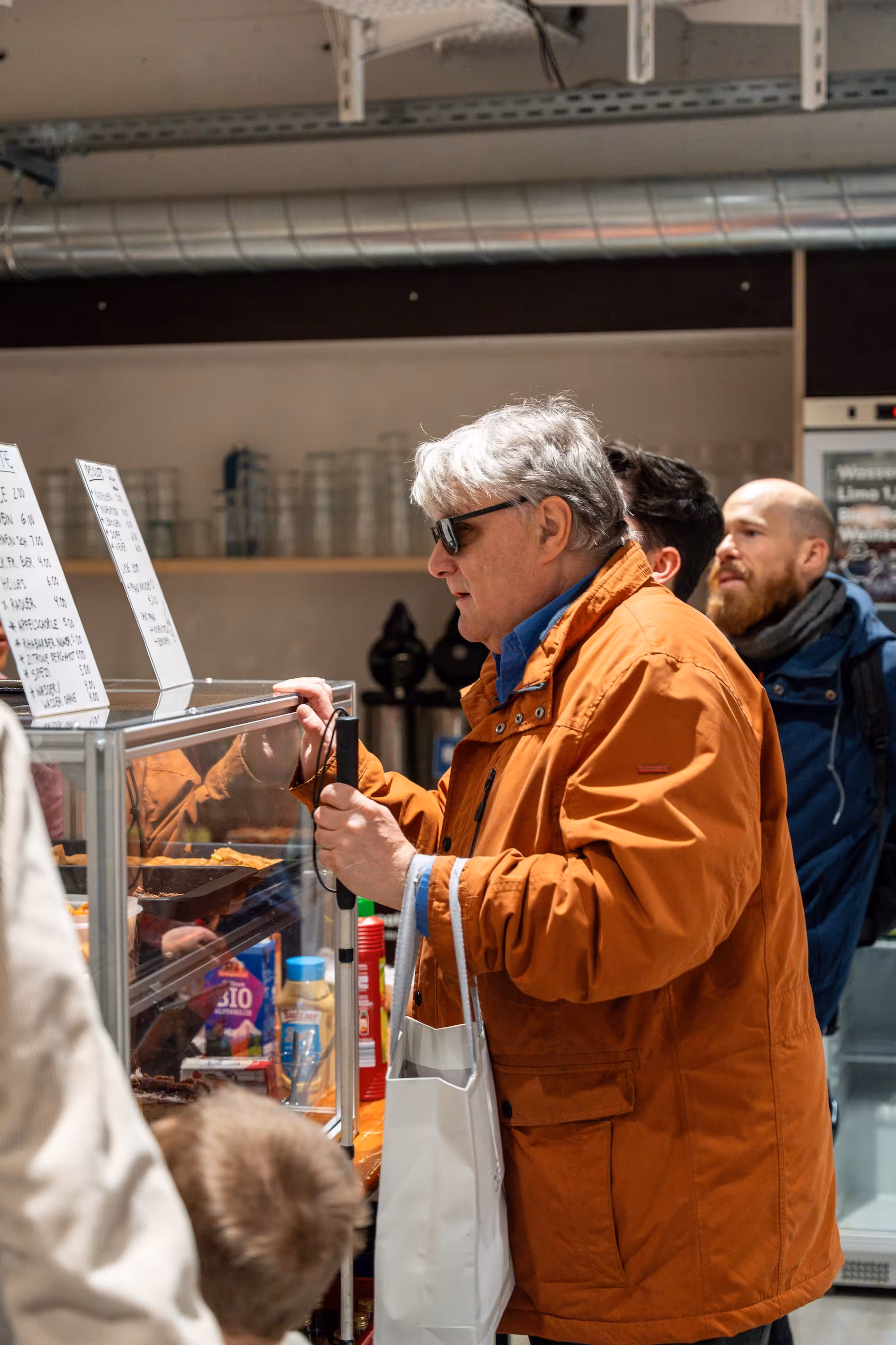 Sehbehinderter Besucher am Kuchenstand beim Secondhand-Basar von Sehbehindert – aber Richtig e.V. in München