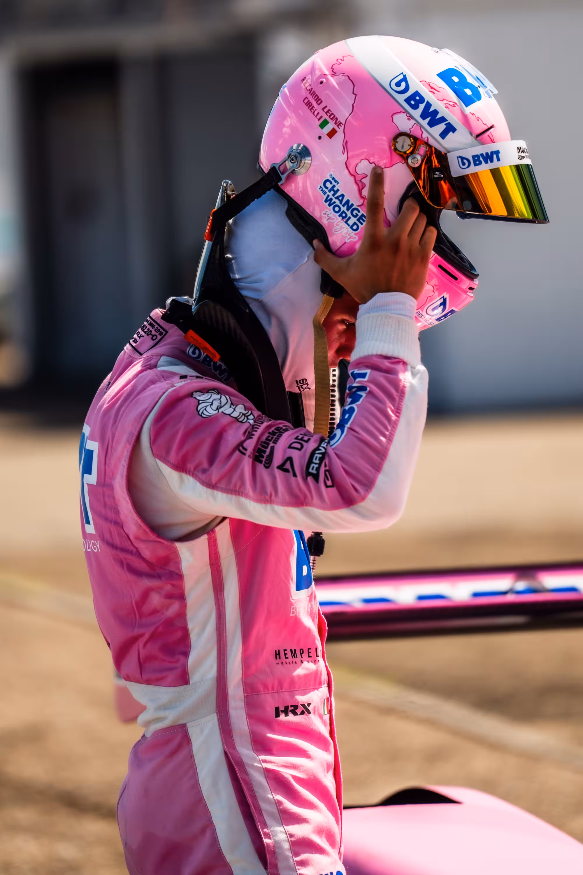 Seitenprofil von Rennfahrer Riccardo Leone Cirelli, der sich seinen pinken Helm absetzt. Er trägt einen passenden BWT-Rennanzug.
