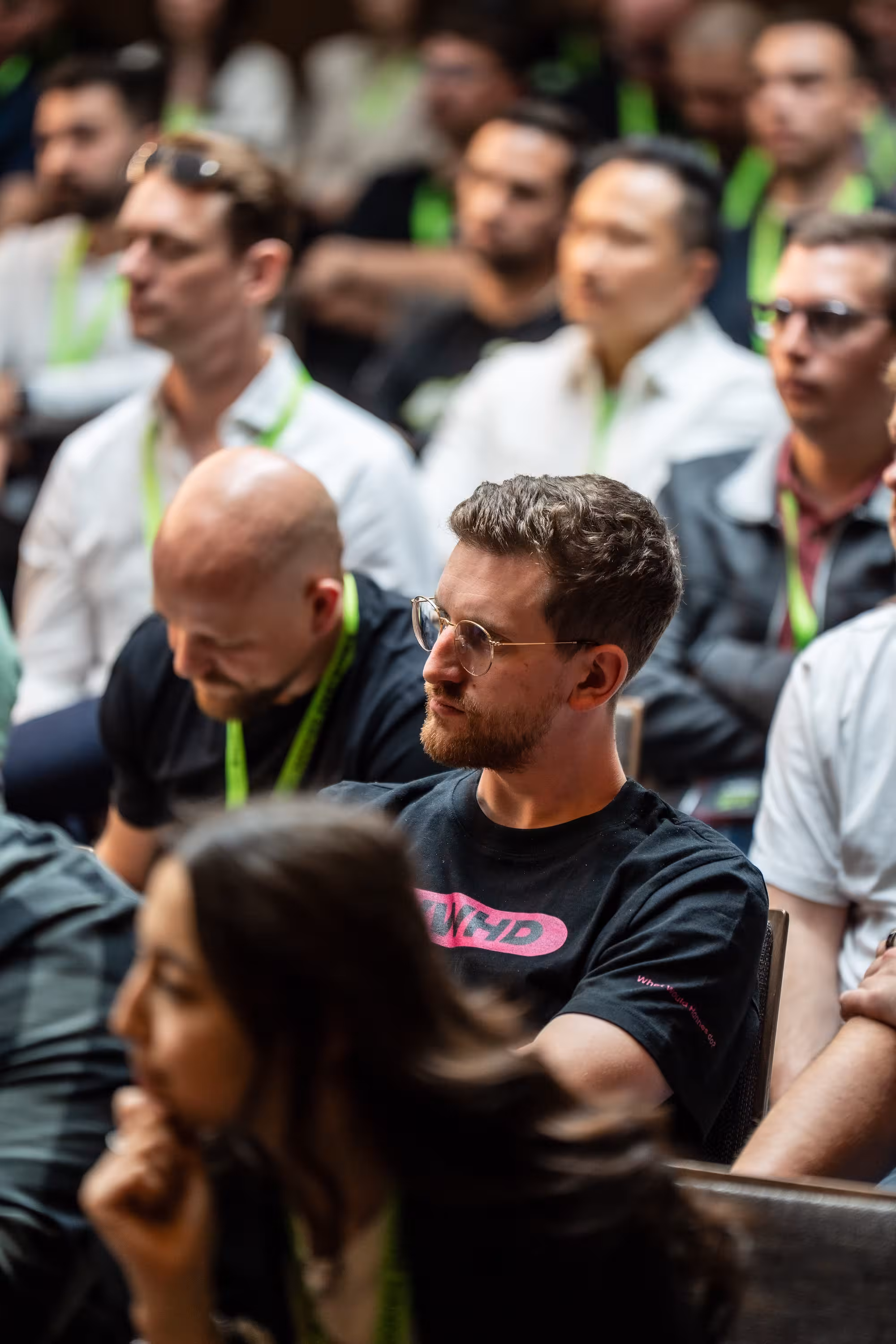 Roman Nenstiel, Gründer von Shrymp Commerce, sitzt konzentriert im Publikum des Hannes Zwetschke Community-Day. Er trägt eine Brille und ein schwarzes T-Shirt mit pinker Aufschrift.