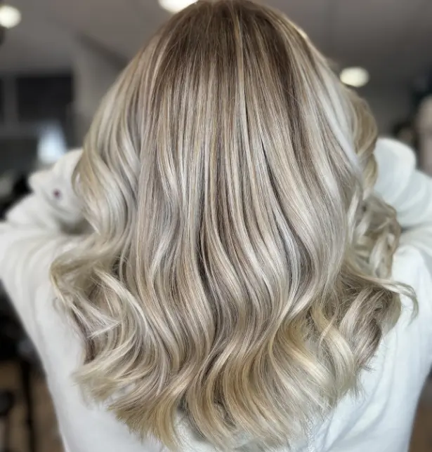 Femme de dos avec un balayage blond réalisé avec des produits wella professionnel sur cheveux mi-longs.