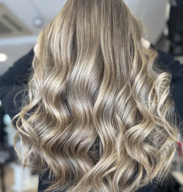 Femme de dos avec un balayage technique sur cheveux longs et ondulés.