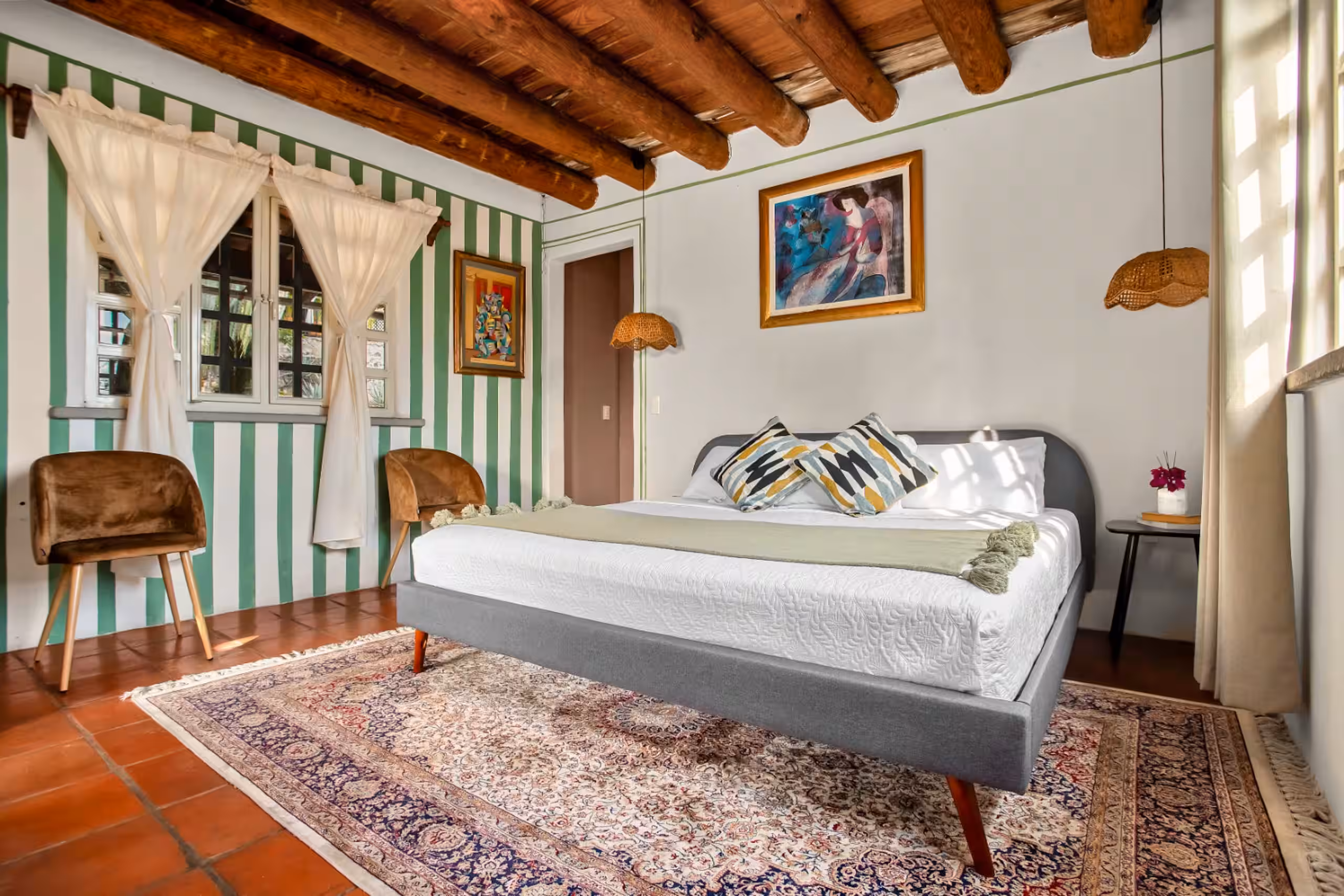 Bedroom with green striped walls and windows onto the hillside.