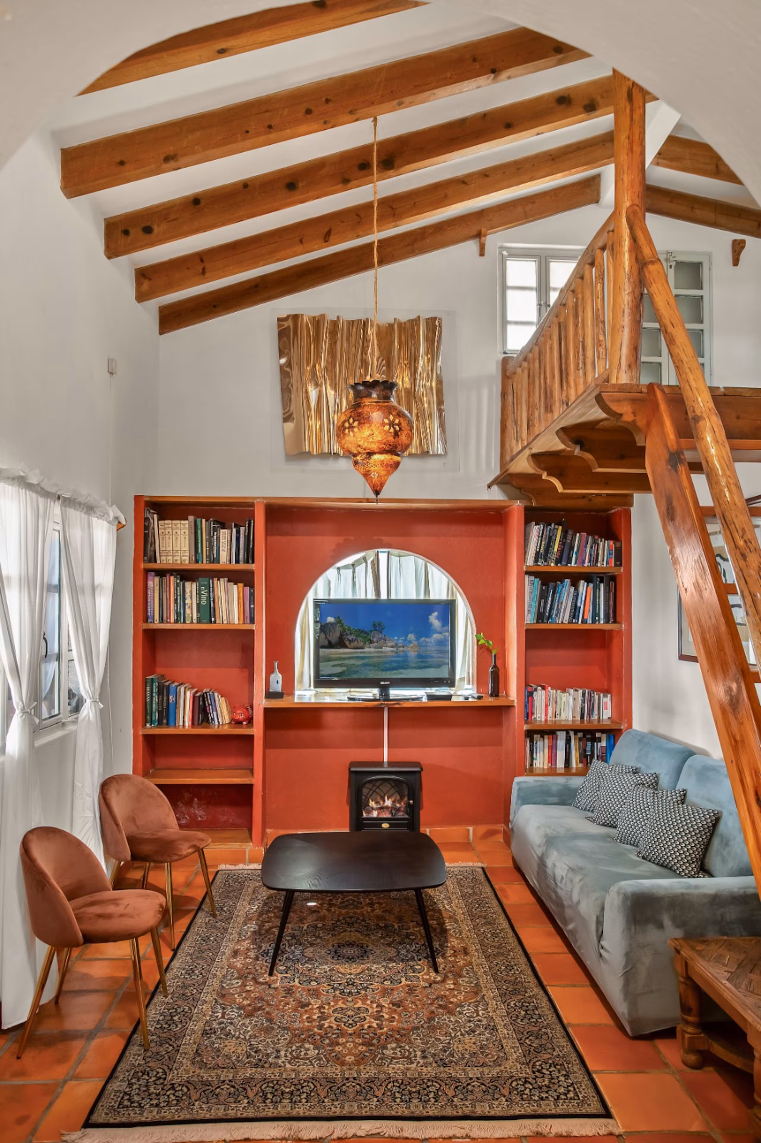 Living room with a fireplace, bookshelves, and a timber staircase.