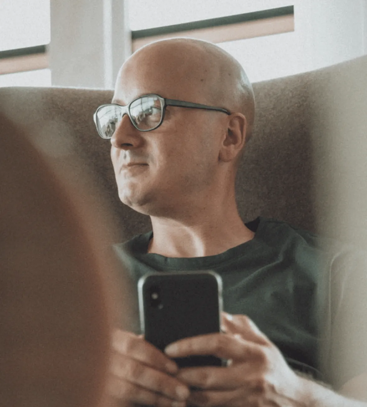 Niko Emran auf einem Stuhl sitzend mit Smartphone