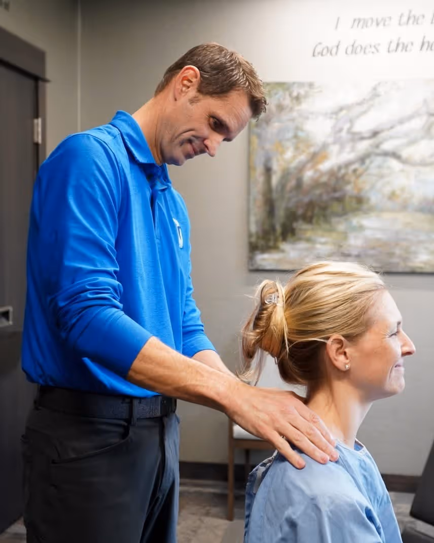 Dr. Ben Gillis of Gillis Family Chiropractic in Wyoming MI performing a chiropractic adjustment on a smiling female patient.
