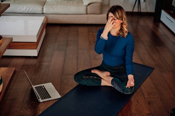 A woman doing alternate nostril breathing under guidance of a coach.