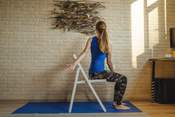 A woman doing the chair spinal twist for weight loss and muscle tone.