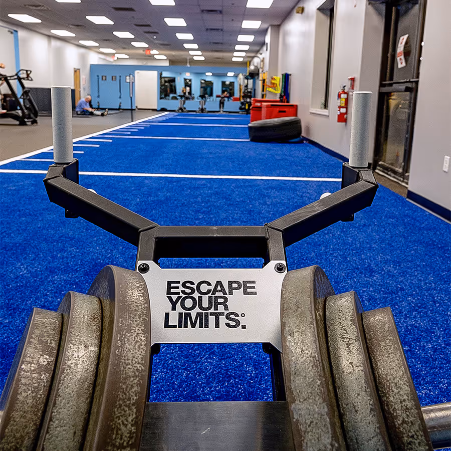 Weighted sled being pushed along the blue athletic turf area