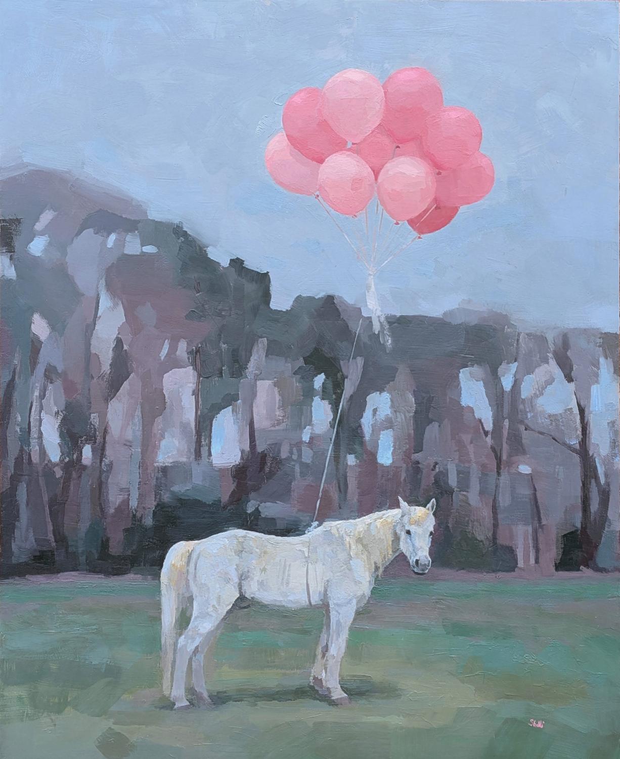 grey-white horse tethered to a bundle of pink balloons standing in a green pasture with treeline in background